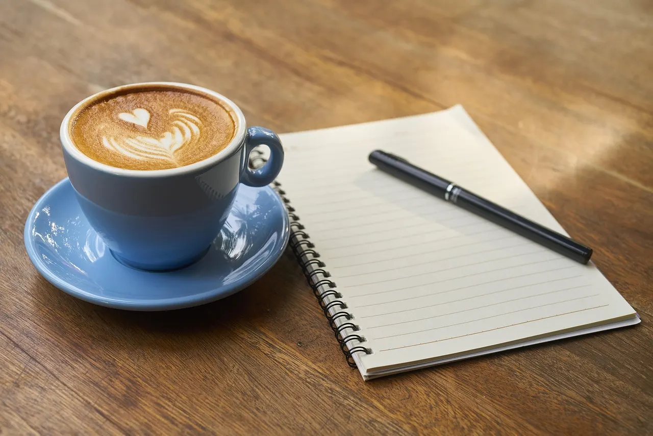 An open notebook with a pen and coffee ready for planning